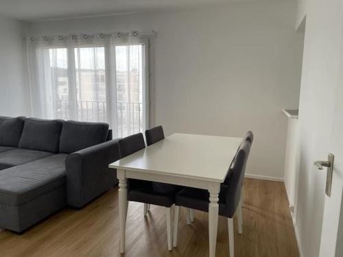 uma sala de estar com uma mesa e um sofá em Appartement spacieux et cosy 20 min to Paris & JO 2024 em Sannois
