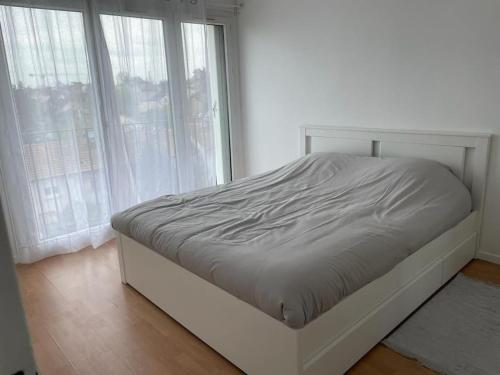 uma cama branca num quarto com janelas em Appartement spacieux et cosy 20 min to Paris & JO 2024 em Sannois