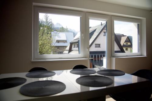 - une table à manger avec 4 chaises et 2 fenêtres dans l'établissement Apartamenty Taternickie, à Zakopane