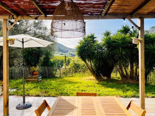 un patio con sombrilla, mesa y sillas en Loft entre mer et campagne à 5 min d'Ajaccio classé 4 étoiles, en Alata