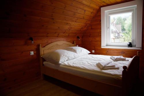 Bett in einem Holzzimmer mit Fenster in der Unterkunft Apartamenty Taternickie in Zakopane