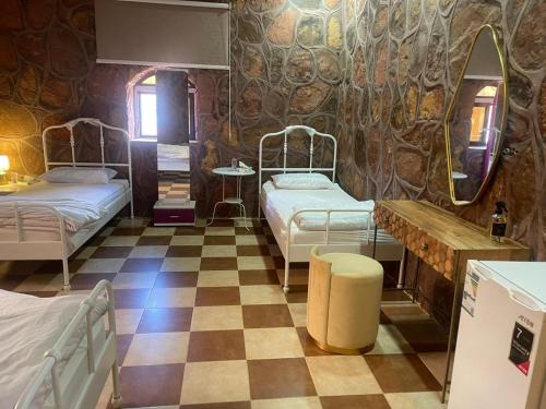 a room with two beds and a checkerboard floor at Red Mountain Farm in AlUla