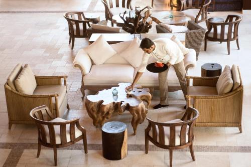 a man is working on a table in a room with chairs at STORY Seychelles in Beau Vallon