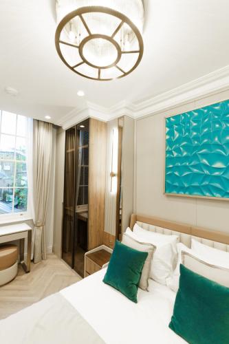 a bedroom with a white bed and a chandelier at Holland Park Residence in London