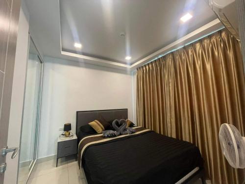 a bedroom with a black bed and a window at Condo Arcadia Beach jomtien pattaya in Pattaya South