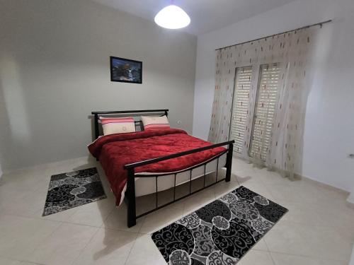a bedroom with a bed with red sheets and pillows at Villa Lediana in Delvinë