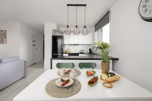 a white kitchen with a table with food on it at TS Hello City Apartment in Szczecin