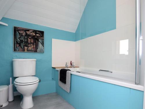 uma casa de banho azul com um WC e uma banheira em 6 Bed in Wroxham 72652 em Hoveton