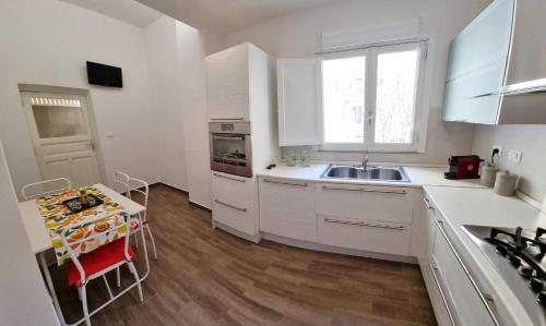 kuchnia z białymi szafkami, zlewem i stołem w obiekcie A Vinedda - PROPPRO - Milazzo w mieście Milazzo