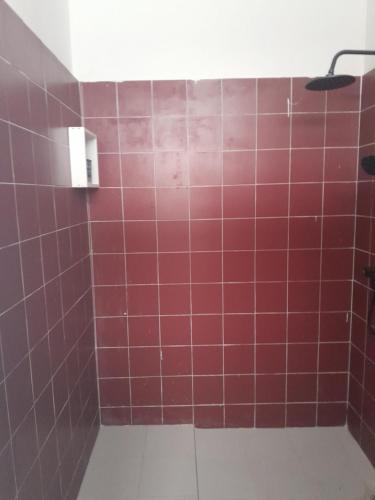 uma casa de banho com uma parede de azulejos vermelhos e um chuveiro em Pied a terre in Ouakam em Ouakam
