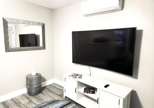 uma sala de estar com uma televisão de ecrã plano na parede em Beautiful Guesthouse, Sleeps 4 - Kitchen, Private Laundry, AC, Parking, 65' TV, Close to Stores, Restaurants & Beach em Long Beach