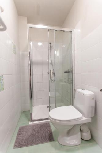 a white bathroom with a shower and a toilet at Pokoje Przy Plaży in Mielno