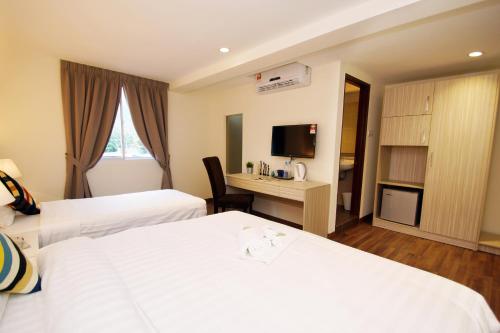 a hotel room with two beds and a desk at Good Luck Inn in Ayer Itam