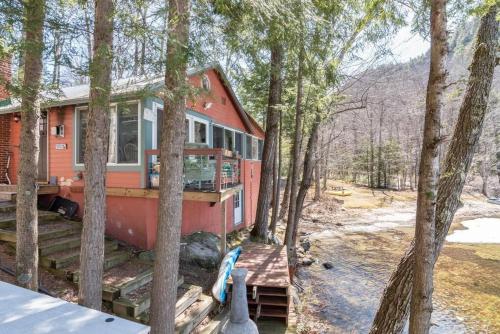 une maison rouge dans les bois avec des arbres dans l'établissement Berta's Lake Front Cottage on Winona Lake!, à Ashland
