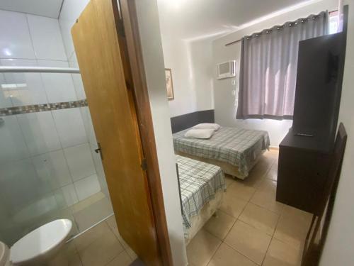a small room with two beds and a shower at Maranata Hotel in Aparecida