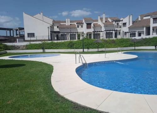 una piscina en un patio con casas al fondo en Casa Rural "Estrella", El Ronquillo, 2 dormitorios, 2 adultos y 2 niños, en Sevilla