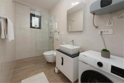 a white bathroom with a sink and a toilet at Sea Star Apartment in Cavtat