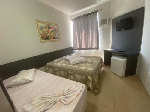 a hotel room with two beds and a television at Maranata Hotel in Aparecida