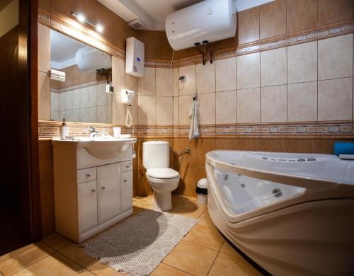a bathroom with a tub and a toilet and a sink at Pokoje Przy Plaży in Mielno
