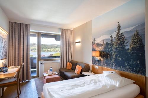 Habitación de hotel con cama y sofá en Aktivhotel Föttinger, en Steinbach am Attersee