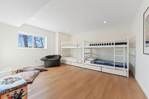 2 literas blancas en una habitación con suelo de madera en Stillness on the Shore - Fabulous family cottage en Parry Sound