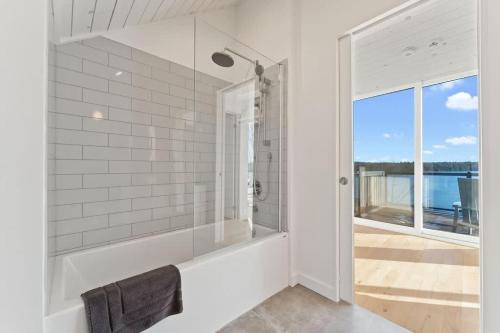 baño blanco con bañera y ventana en Stillness on the Shore - Fabulous family cottage en Parry Sound