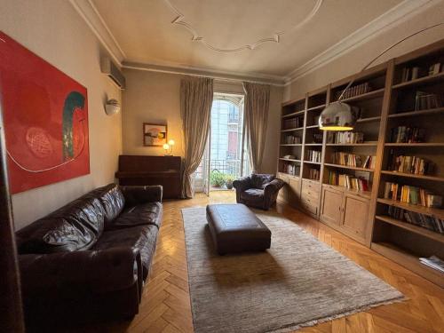 a living room with a leather couch and book shelves at Eleganza Liberty a due passi da Porta Susa e Metró in Turin