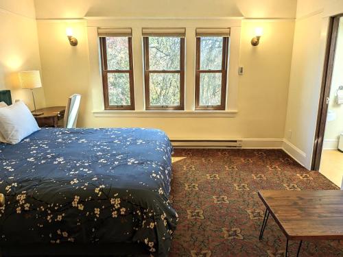 a bedroom with a bed and a table and windows at Bluebird Guesthouse in Portland