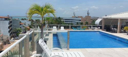 a swimming pool on a balcony with two chairs and a palm tree at Hotel Yaque Club in Porlamar