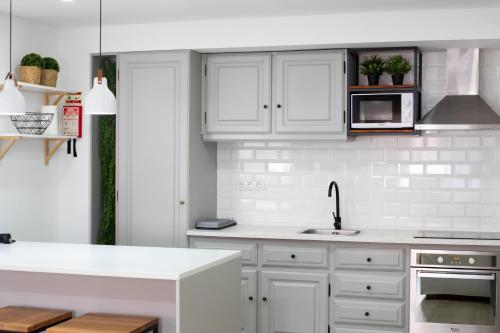 a white kitchen with white cabinets and a sink at Earth Element Apartment in Peniche