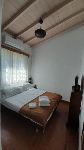 Casa de Huéspedes Muñiz sobre parque de 1000m2, 1 dormitorio, 20m2 cubiertos, baño con ducha, pileta cilíndrica de 3x076 في Muñiz: غرفة نوم بها سرير كبير عليه منشفتين