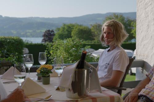 a woman sitting at a table with a bottle of wine at Aktivhotel Föttinger in Steinbach am Attersee