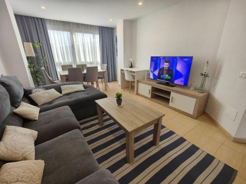 uma sala de estar com um sofá e uma televisão em Vacacional familiar al mar em Candelaria