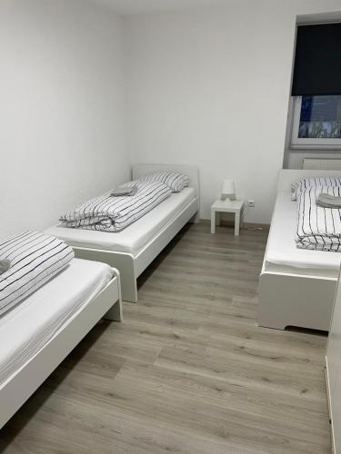 two beds in a room with wooden floors at Ferien - Wohnung In Kassel Waldau Zentral in Kassel