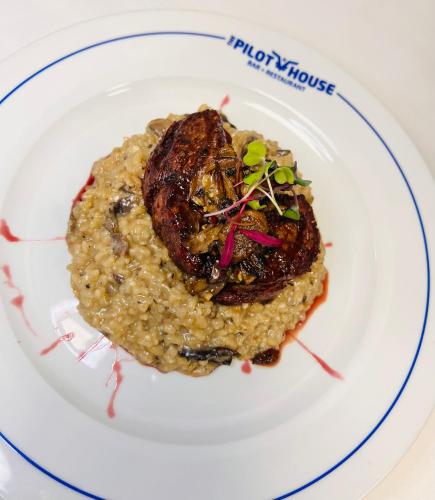 a plate of food with a piece of meat on risotto at Wyndham Garden Miami International Airport in Miami