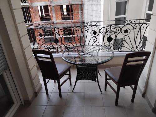 a glass table and chairs on a balcony with a window at apartment gjilan in Gjilan