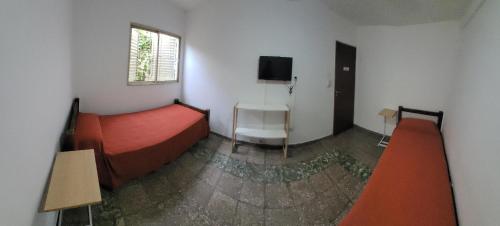 a bedroom with a red bed and a tv on the wall at HOTEL RESIDENCIAL CAMACHO in Cordoba