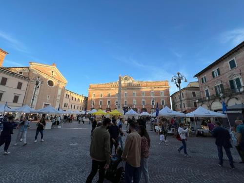 a group of people walking around in a square with tents at La Dimora del Centro in Iesi