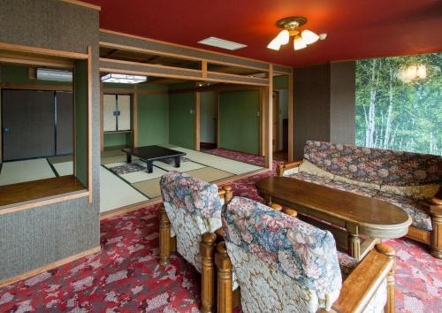 a living room with a couch and a table and chairs at Izuito Onsen Daitokan in Ito