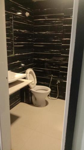 La salle de bains est pourvue de toilettes et d'un mur noir. dans l'établissement Abhinandan guesthouse, à Gondia