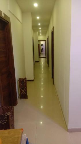 un long couloir avec des murs blancs et un long étage dans l'établissement Abhinandan guesthouse, à Gondia