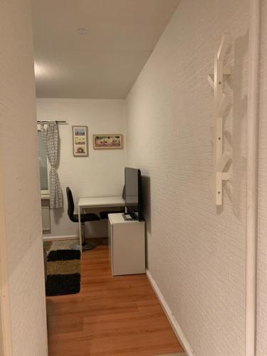 Habitación pequeña con escritorio y TV en la pared. en Charming Studio in kista, en Estocolmo