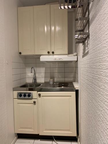 una pequeña cocina con armarios blancos y fregadero en Charming Studio in kista en Estocolmo