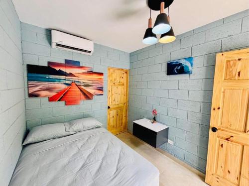 a bedroom with a bed and a painting on the wall at Hostal Camila’s in Tamanique