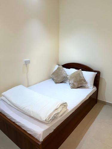 a bed with white sheets and two pillows on it at Small Room shared bath with beach access for single person or short stay couplesغرفة صغيرة مع حمام مشترك مع إمكانية الوصول إلى الشاطئ لشخص واحد أو للأزواج الذين يقيمون لفترة قصيرة in Ajman