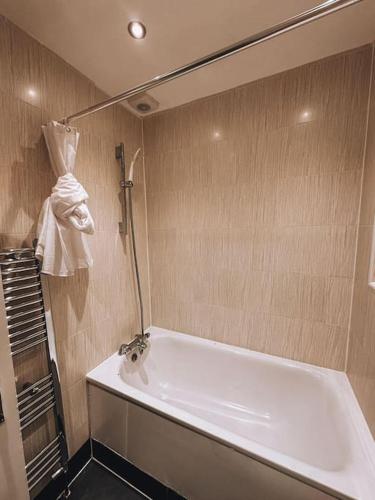 La salle de bains est pourvue d'une baignoire et d'une serviette accrochée au mur. dans l'établissement Modern 2 bedroom Flat in Balham, à Londres