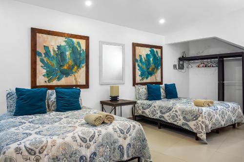twee bedden in een kamer met blauwe kussens bij Villa Turquesa 56 - Playa Arcangel in Rosarito