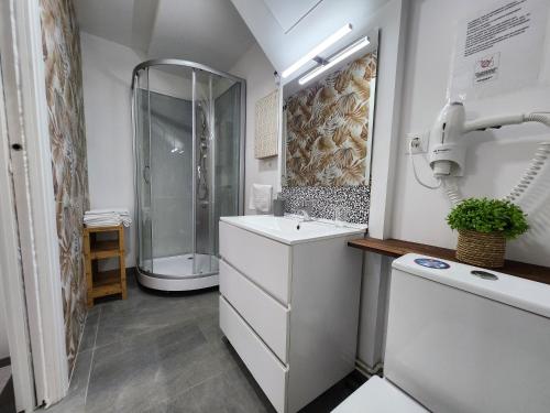 baño blanco con ducha y lavamanos en Estudios Playa de Covachos, en Soto de la Marina