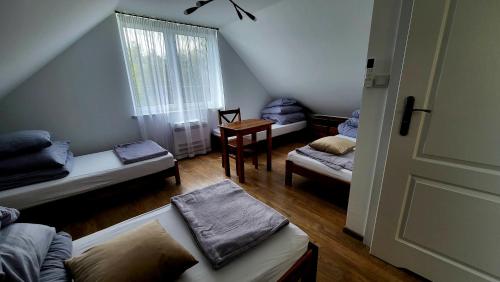 a room with three beds and a table and a window at Mościce Dolne 69 in Nowosiółki