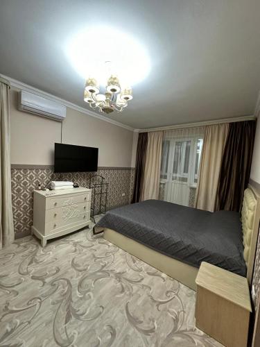 een slaapkamer met een bed, een dressoir en een televisie bij Люкс в центре города in Karagandy